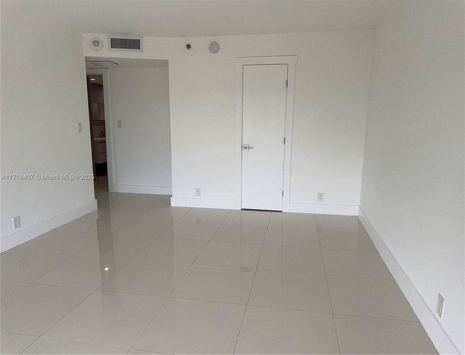 another view of Primary bedroom with closed door to closet with the en-suite bathroom in rear of photo.