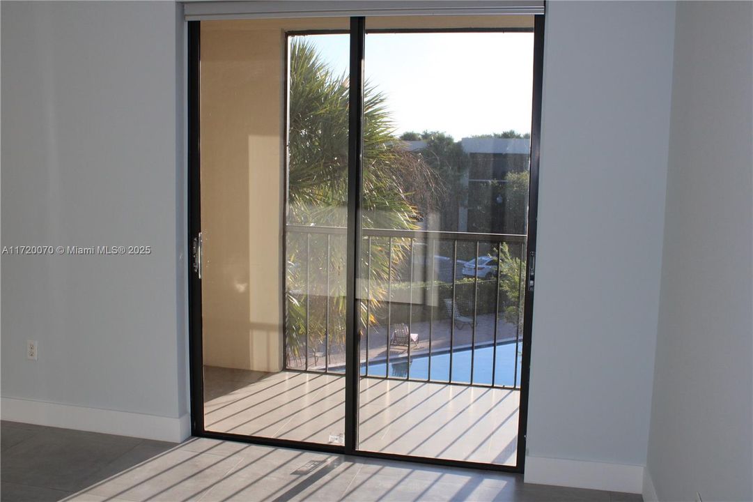 MASTER BEDROOM WITH SLIDING  DOORS TO SCREENED BALCONY AND VIEW OF POOL