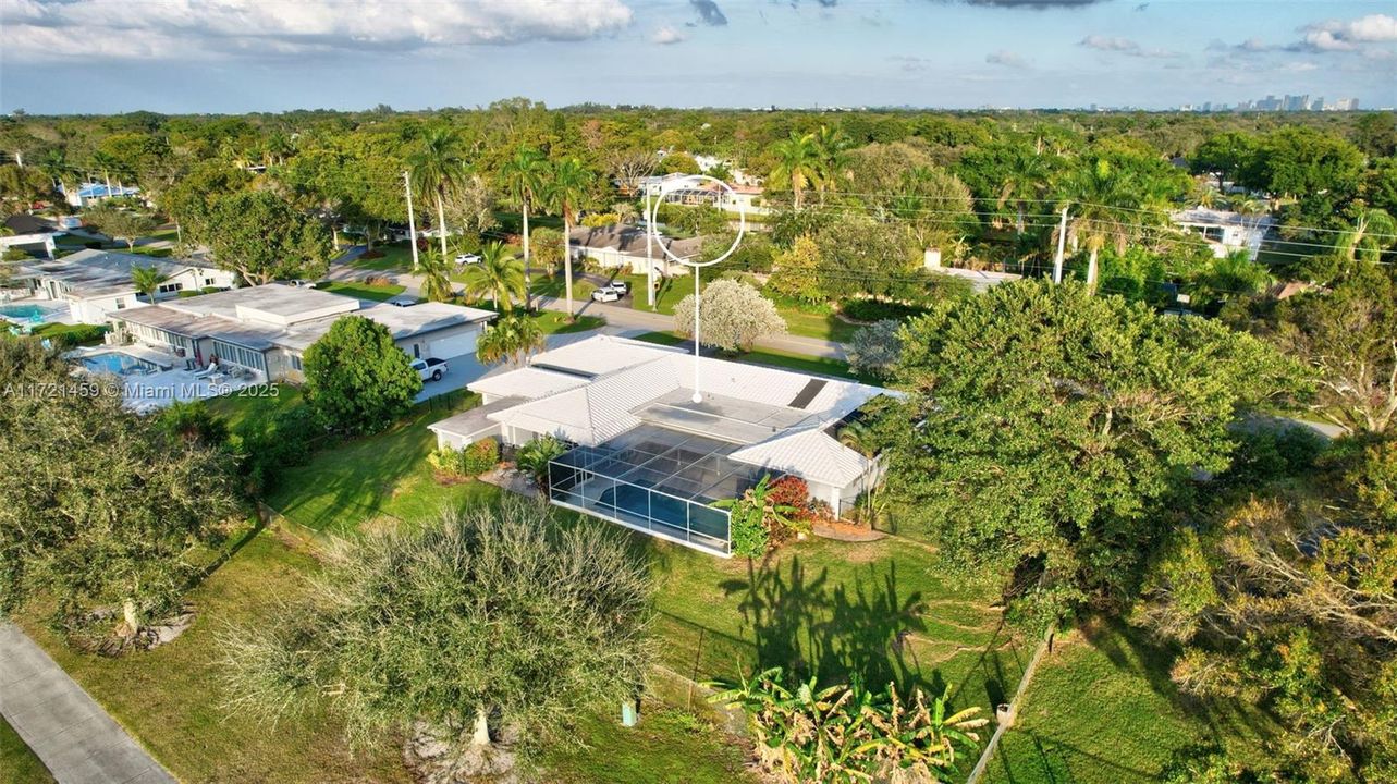 Overhead view of the home. Large screen enclosed pool area. White tile roof