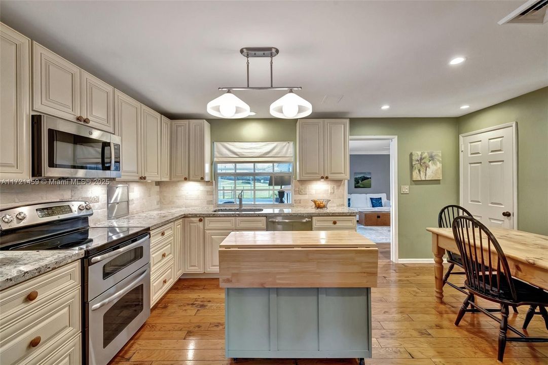 Updated kitchen with double oven and island cart to use as counter seating w/ window to the backyard. Kitchen leads into den off patio area