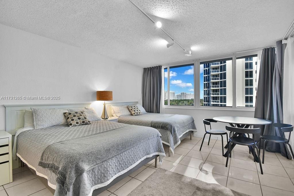 Spacious bedroom with floor-to-ceiling windows, abundant natural light, and stunning city views. Ideal coastal retreat in Sunny Isles Beach.