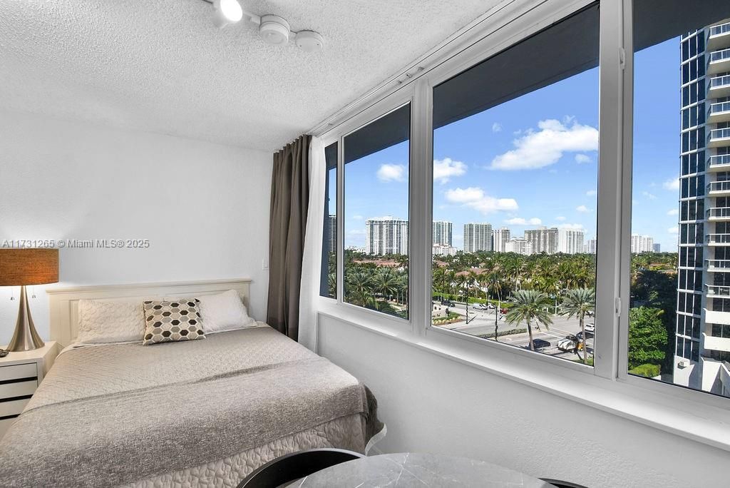 Elegant primary suite with contemporary design, sleek finishes, and bright corner windows overlooking the oceanfront skyline.