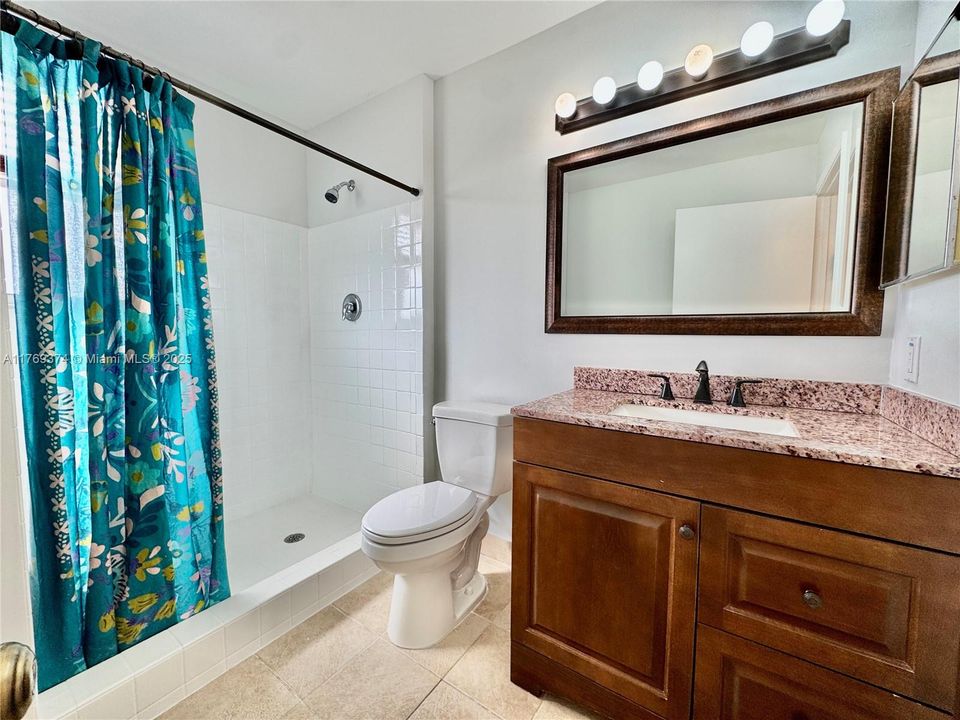 Primary bathroom with tiled walk-in shower with built-in seat.