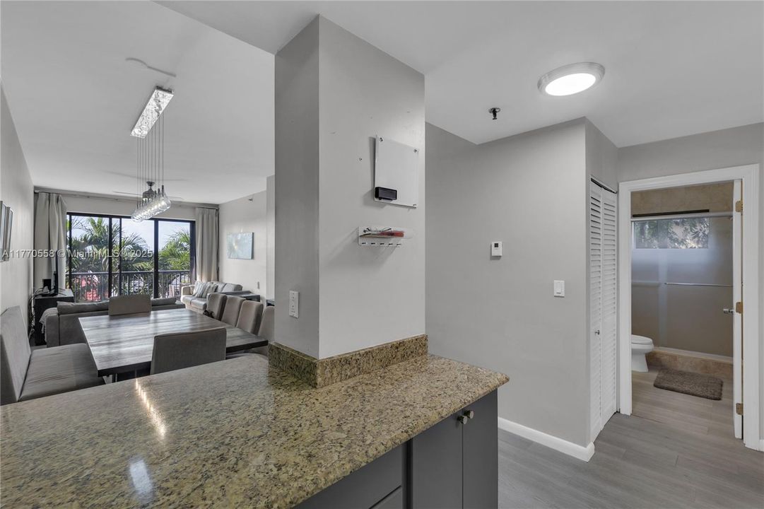 Shows exit from kitchen looking into the guest bathroom, dining/ living room in front