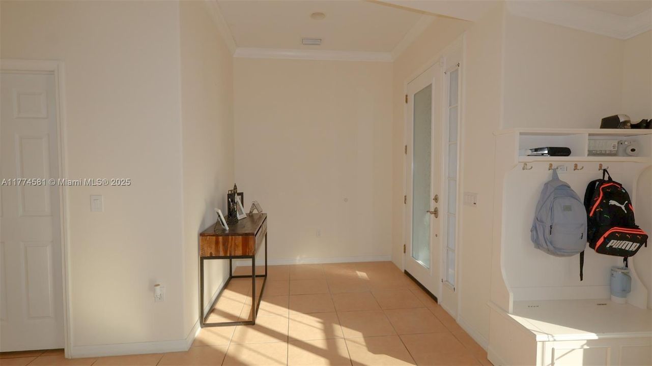 Corridor with light tile patterned flooring, baseboards, and ornamental molding