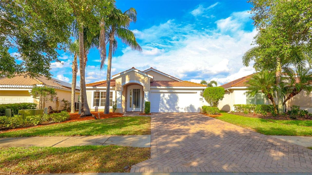 Mediterranean / spanish-style house featuring stucco siding, an attached garage, a tiled roof, driveway, and a front lawn