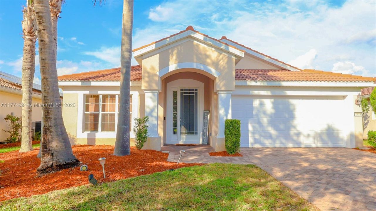 View of front facade featuring stucco siding, a garage, a tiled roof, and decorative driveway