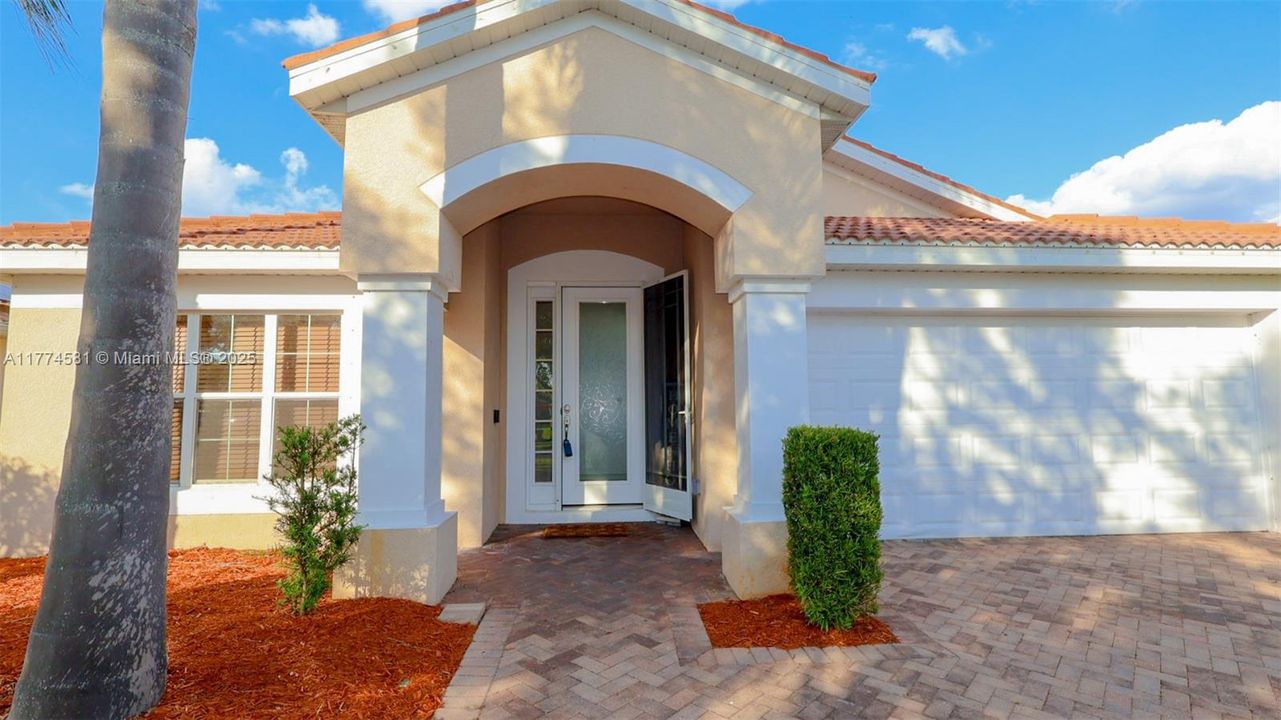 Property entrance with a tile roof, stucco siding, and an attached garage