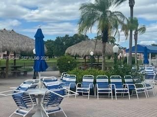 Paver patio area featuring thatch-roofed cabanas and mature palm trees