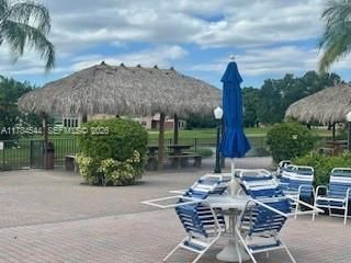 Outdoor patio featuring interlocking paver stones, thatched-roof gazebos, and ornamental lamppost lighting