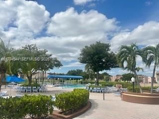 Swimming pool with shaded canopy, paver patio, and mature landscaping