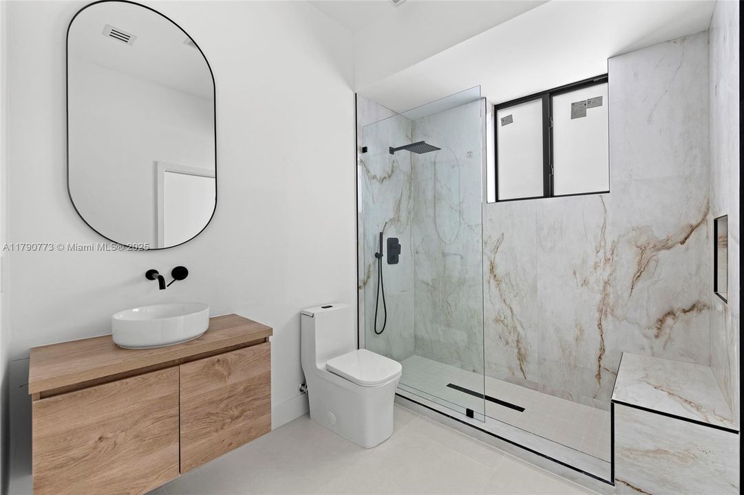 Finished with exquisite Taj Mahal Quartzite, the secondary bathroom offers a spacious shower with a premium rainfall showerhead, delivering comfort and style.