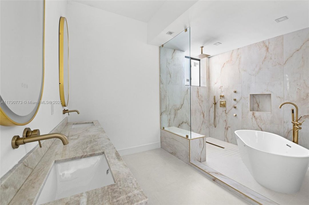 The primary bathroom is beautifully designed with exquisite Taj Mahal Quartzite, featuring a freestanding soaking tub and an oversized shower equipped with a rainfall showerhead and body jets for a true spa-like experience.