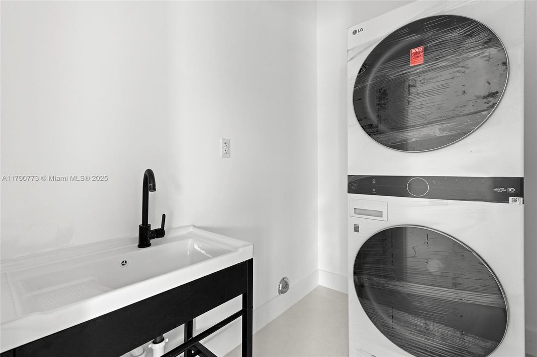 Spacious laundry room equipped with top-of-the-line LG washer and dryer, a utility sink, and ample space for added convenience and functionality.