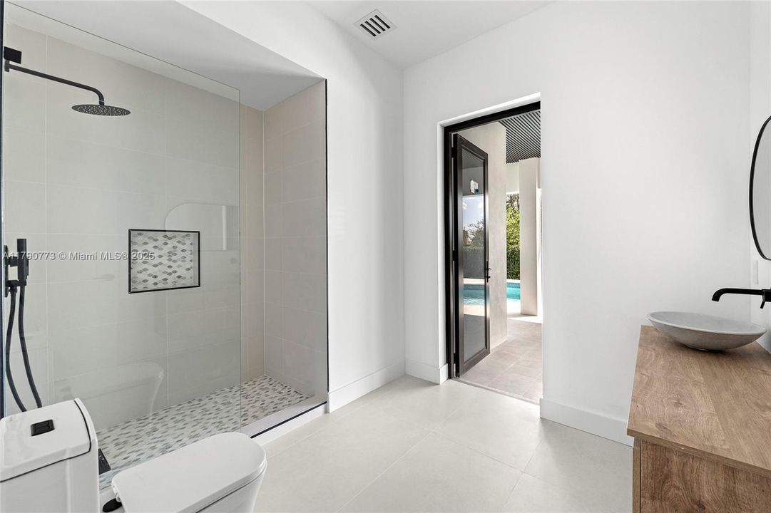 Cabana bath featuring a spacious rainfall shower and a handheld showerhead, combining luxury and convenience for seamless indoor-outdoor living.