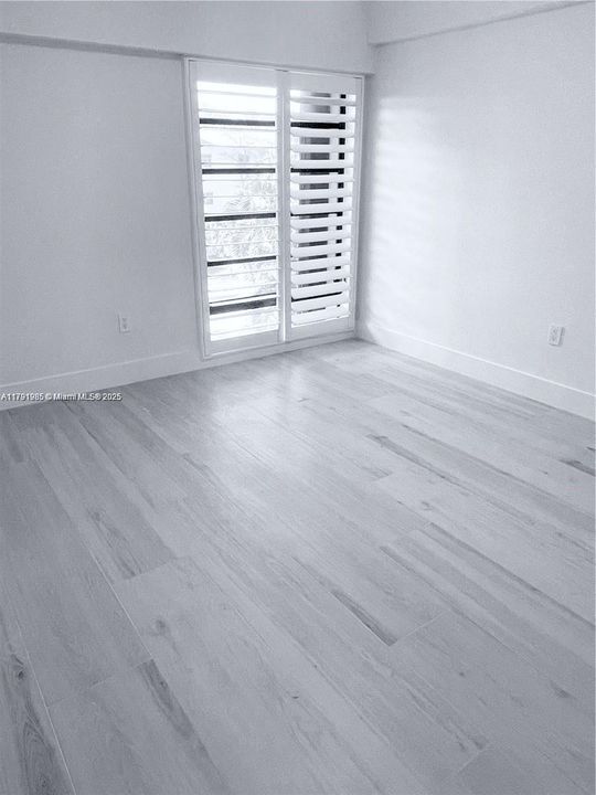 2nd bedroom with floor to ceiling windows, custom built closet system and plantation shutters.
