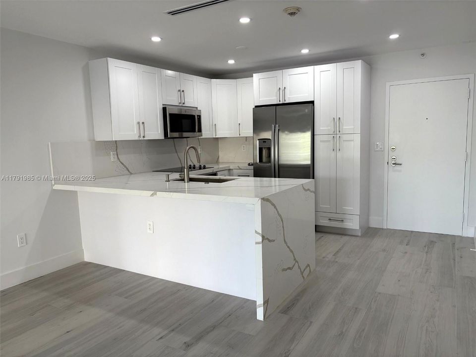 Open kitchen with island, quartz countertops and backsplash, brand new GE stainless steel appliances!
