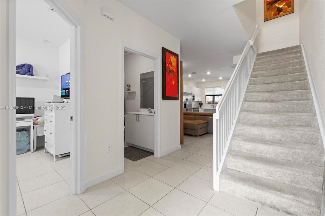 Upon entering the home, you are welcomed by a staircase leading to the second floor. To your left, there is a convenient bedroom on the main level, perfect for guests or a home office, which shares a full bathroom with the social area.
