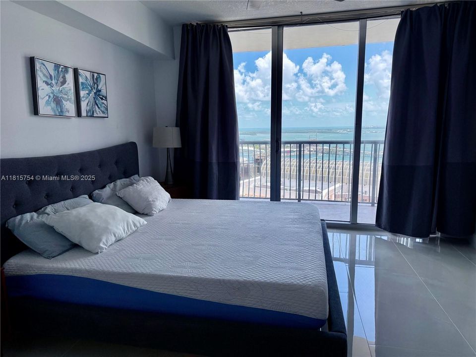 Bright bedroom with full-length windows showcasing panoramic Miami views — perfect for enjoying sunrise over the bay.