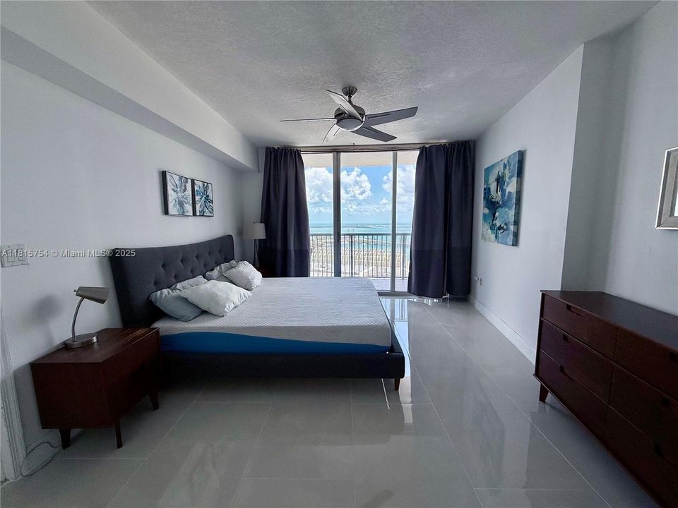 Large primary bedroom with direct balcony access, city and bay views, and space for a king bed — tranquil high-rise retreat.
