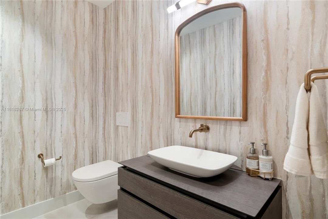 Designer powder room with vessel sink, wall-mounted faucet, and textured wallpaper.