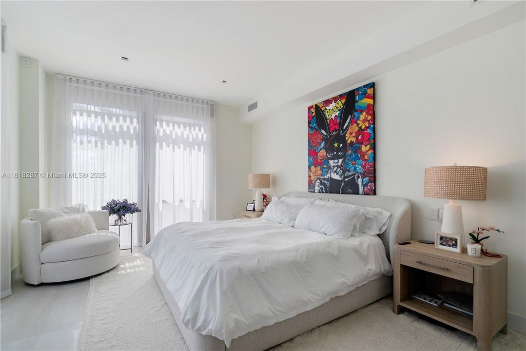 Bright, calming primary bedroom with floor-to-ceiling windows, soft natural light, and space for a reading or seating nook.