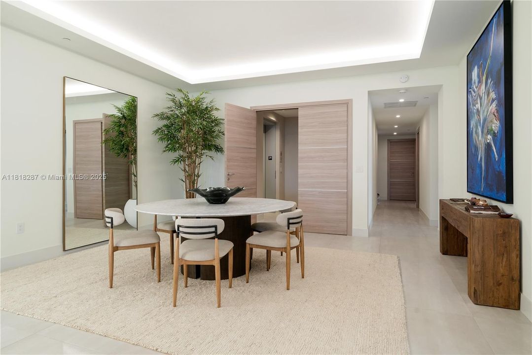 Bright dining space with recessed lighting and a large mirror wall enhancing volume and flow.