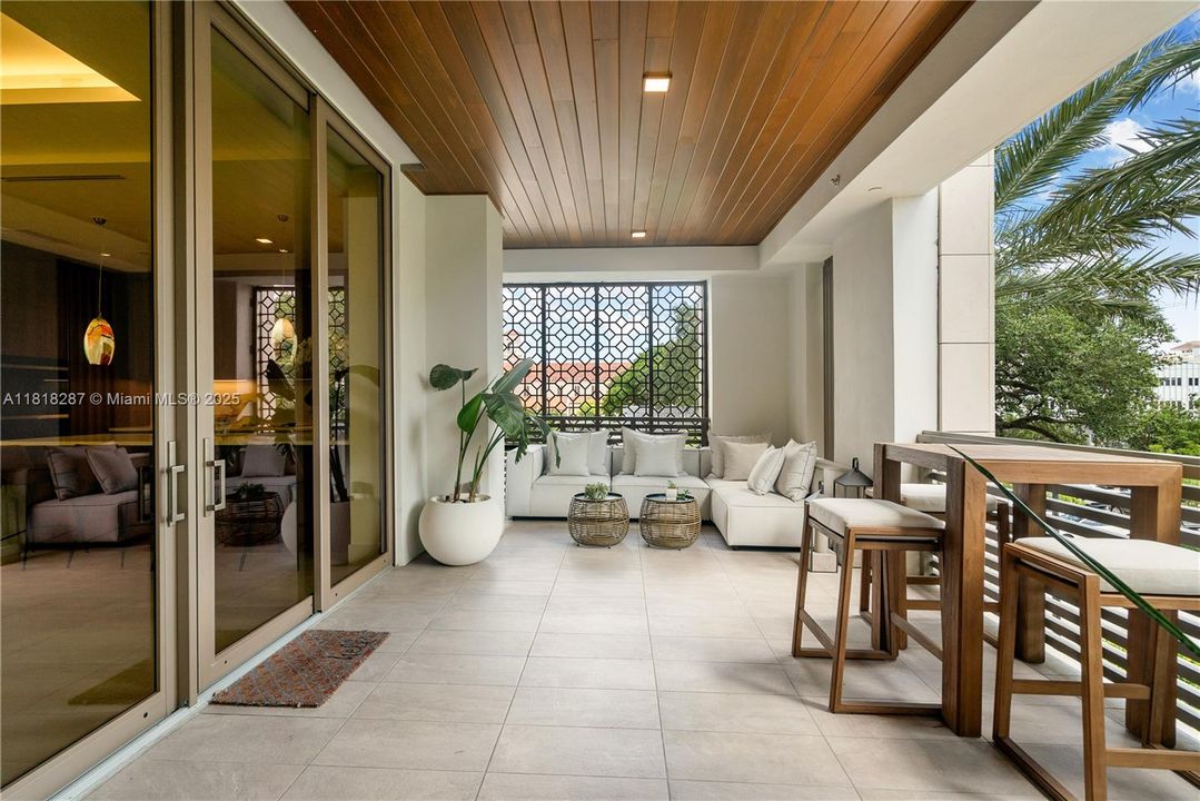 Elegant covered terrace with warm wood ceiling, offering a private outdoor retreat surrounded by lush greenery.