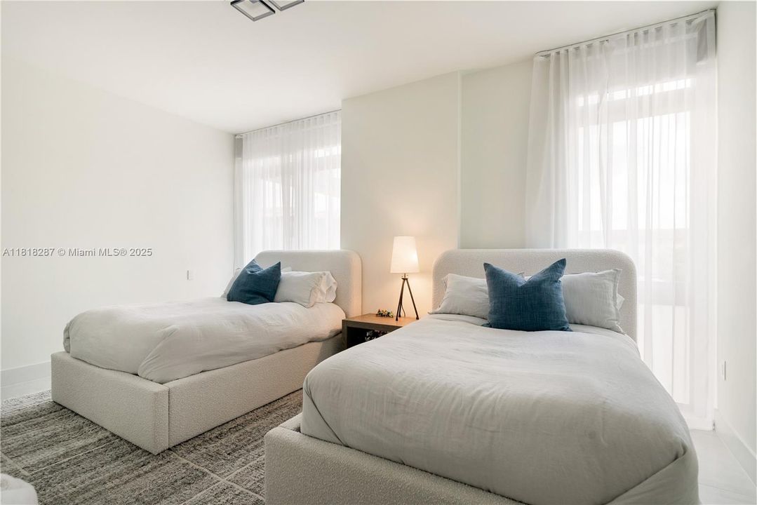 1st bedroom with large windows, soft natural light, and neutral palette.