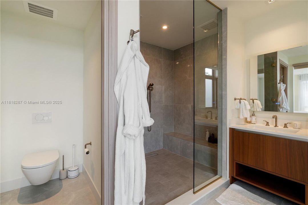 Spa-inspired bath featuring a freestanding soaking tub, glass-enclosed walk-in shower with built-in bench, and a private water closet.