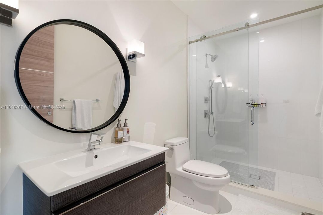 Modern bathroom with glass-enclosed shower and contemporary vanity.