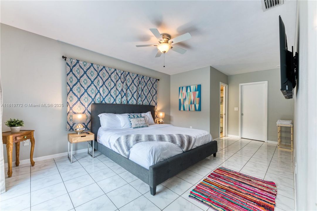 King bed & en-suite bathroom with a step-in shower. The room has a ROKU TV for streaming and access to the outdoor pool deck.