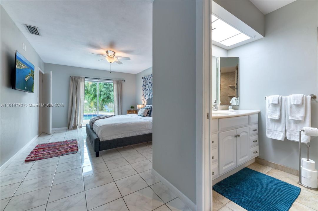 King bed & en-suite bathroom with a step-in shower. The room has a ROKU TV for streaming and access to the outdoor pool deck.