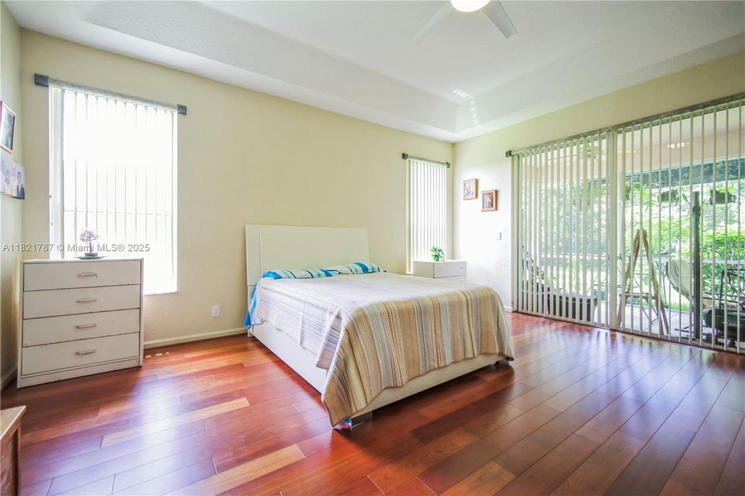 Huge primary bedroom with beautiful wood floors & custom blinds on sliding door & windows.