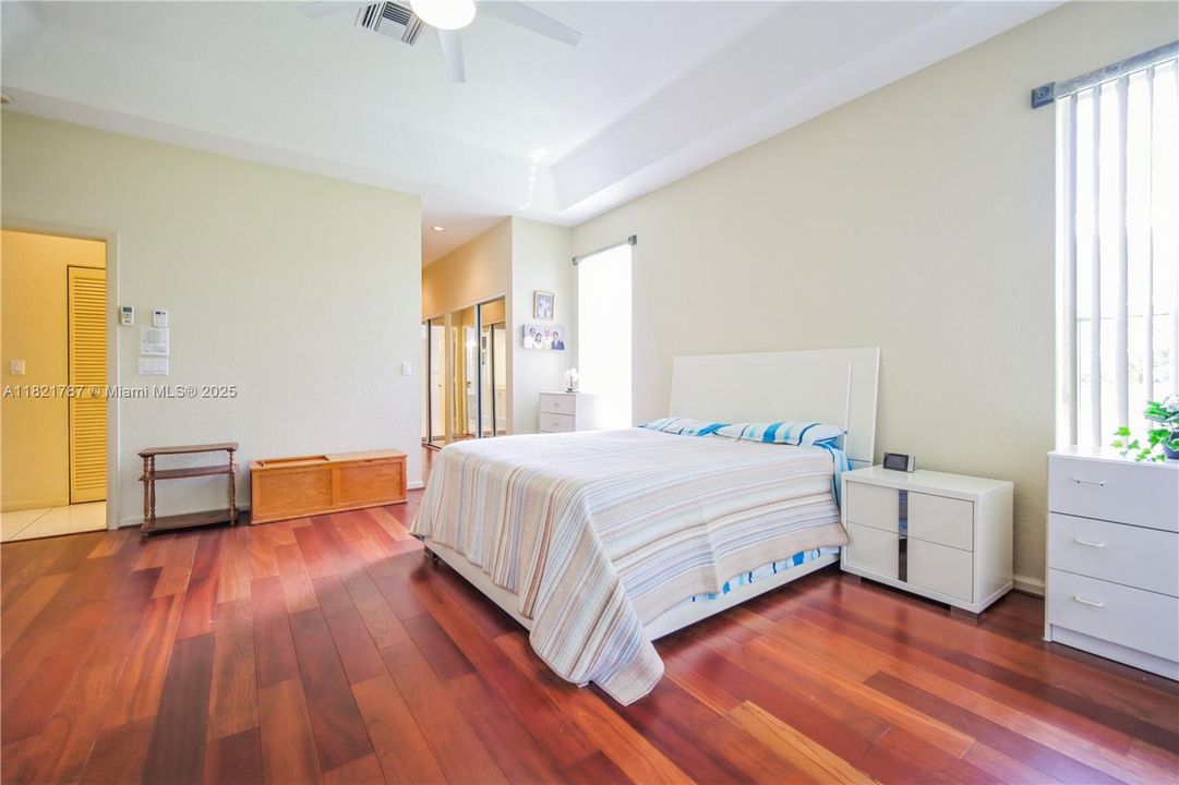 Huge primary bedroom with beautiful wood floors & custom blinds on sliding door & windows.