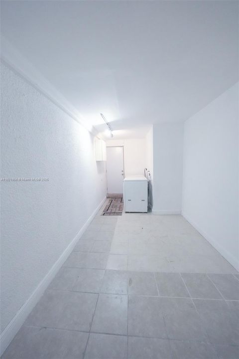 Other side of the converted garage. Washer and dryer are pictured.  Exit to the patio in the rear.
