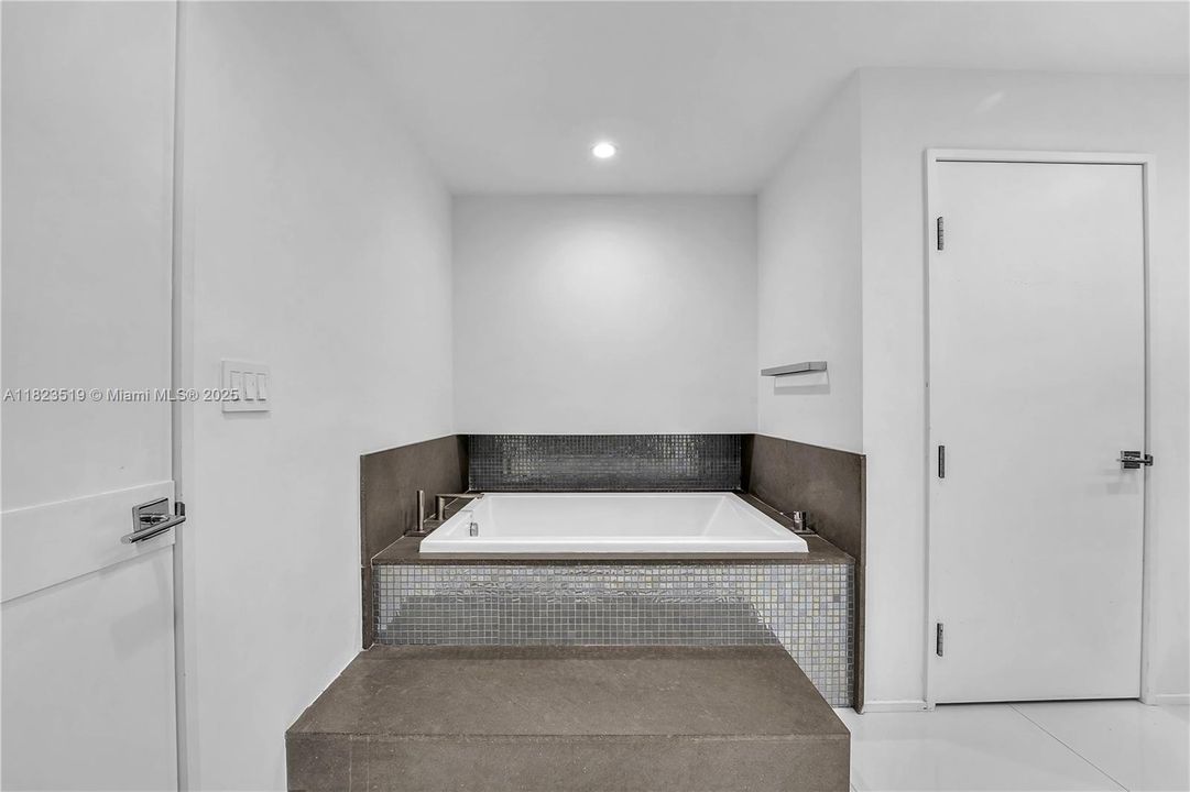 Large plunge tub inside second dual master bathroom.  Storage closet door shown.