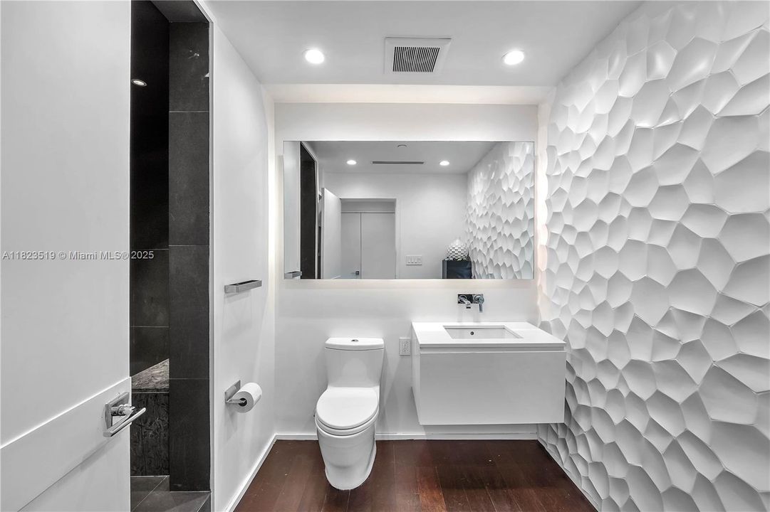 3rd full bathroom shown with shower recessed at left.  Shower has rain spout and shower wand and tiled sitting bench inside.