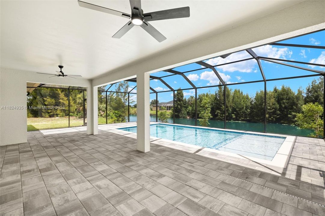 Large lanai area with pavers and canal/pool view