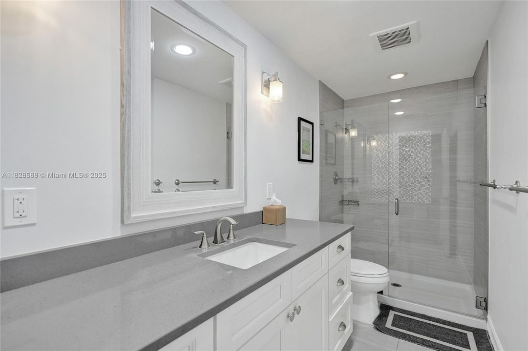 Stylish second bathroom featuring a sleek, modern frameless glass shower with premium fixtures and elegant finishes.