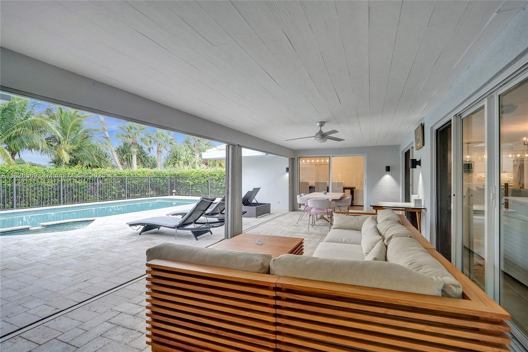 Patio featuring accordion sliding doors with added protection on one side and impact glass sliding doors on the other, combining style, security, and seamless indoor-outdoor living.