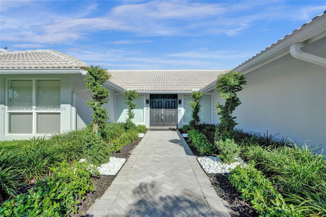 Welcome home! New spiral topiaries, river stones, and thoughtfully designed landscaping create an impressive and welcoming entrance.