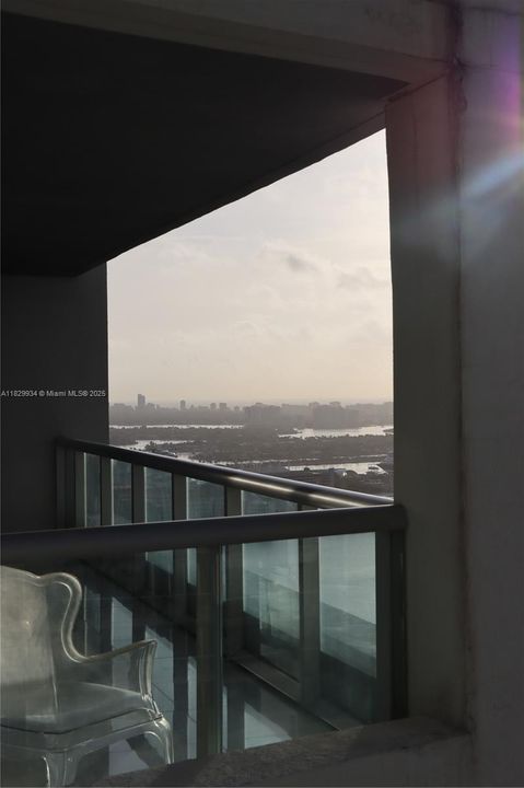 Captured from the secondary balcony looking toward the main terrace, this angle highlights the seamless indoor–outdoor flow and expansive Biscayne Bay views.