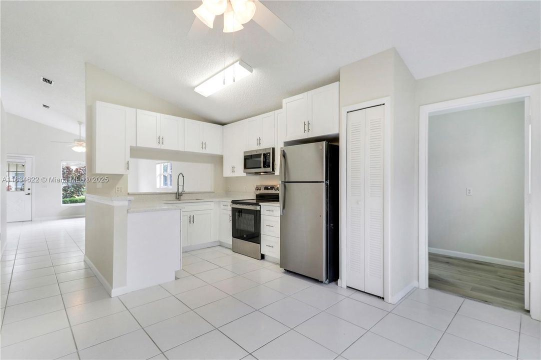 Kitchen view from dining area showing pantry and doorway to the laundry/storage room