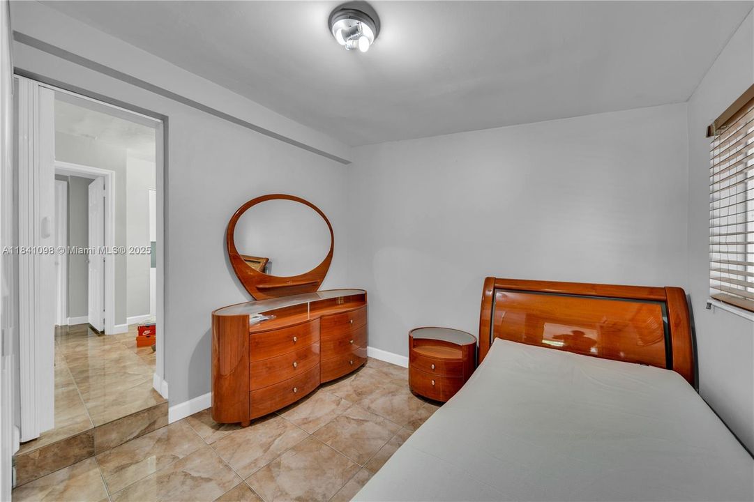 Has its own mini-split A/C unit and a reach-in sliding-door closet featuring solid white and frosted glass panels. Closet offers built-in shelving and drawers for organized storage. Room connects to an adjacent bedroom through a convenient sliding door—perfect for siblings.