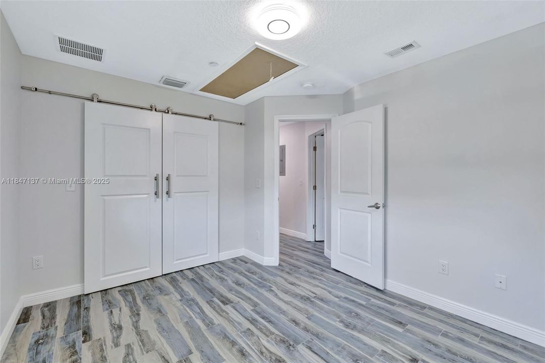 The second bedroom features a valuable attic space accessible via convenient pull-down stairs, offering both practicality and additional storage.