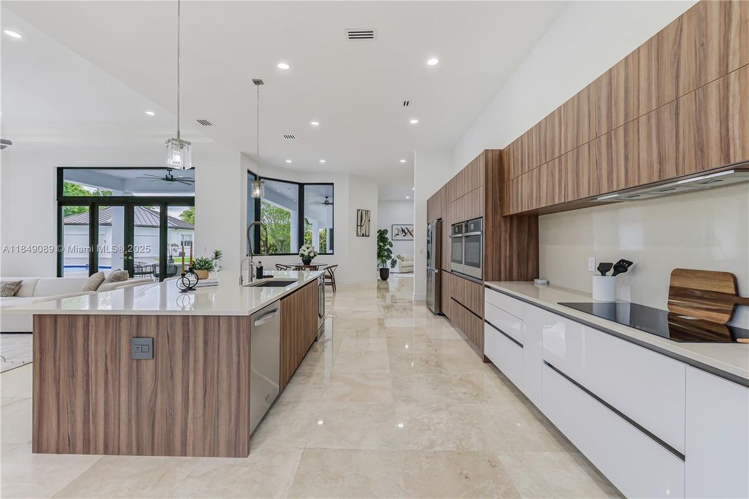 Designer chef’s kitchen with top-of-the-line appliances: induction cooktop, double wall ovens, drawer microwave, dishwasher, washer & dryer, and dual-zone wine fridge.