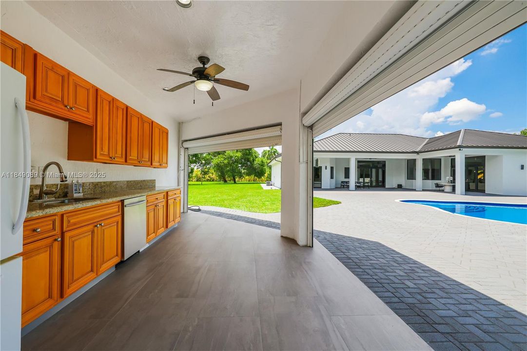 Outdoor kitchen features refrigerator and sink facing the pool.