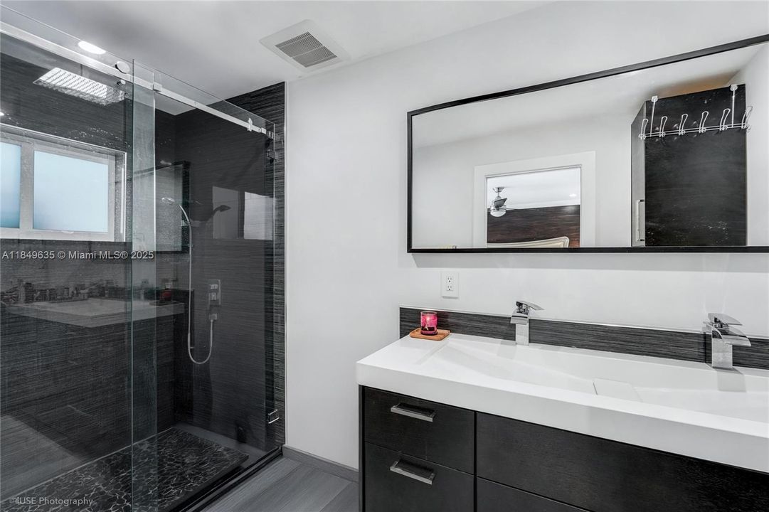 Master bathroom features a double vanity, bold black tile in the shower, and clean white accents.