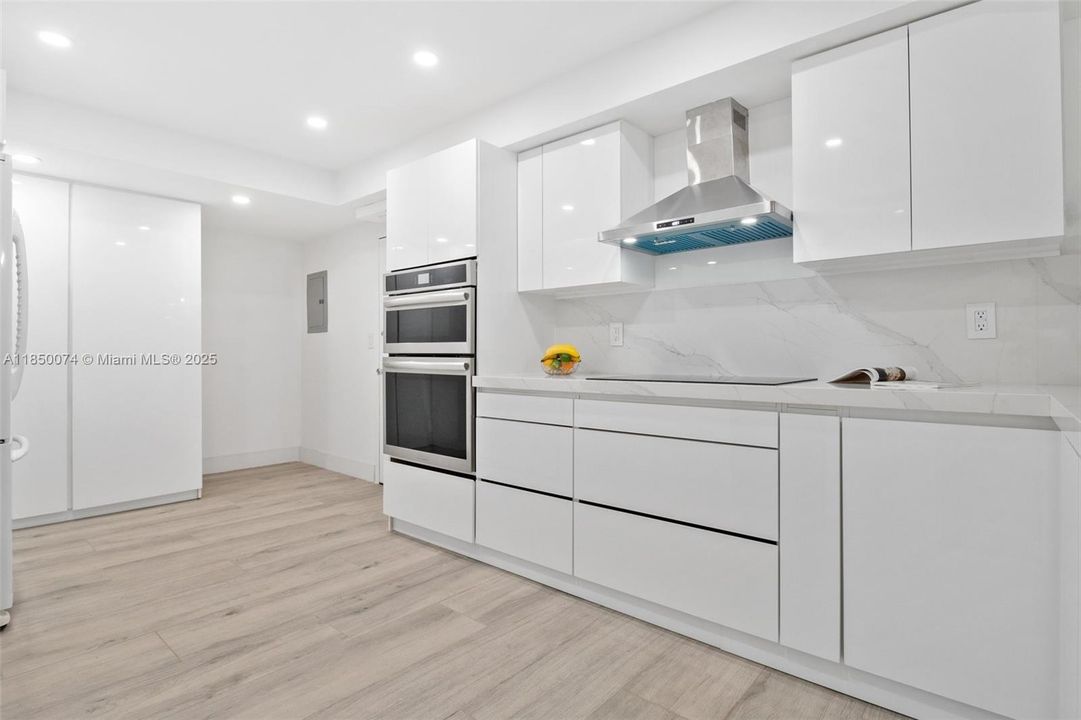 Features stainless steel hood and stove with induction cooktops.